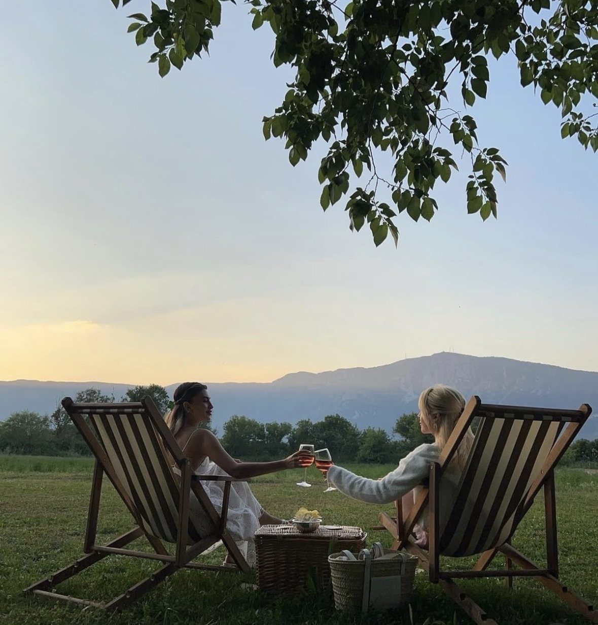 Two friends toasting at sunset in the hills